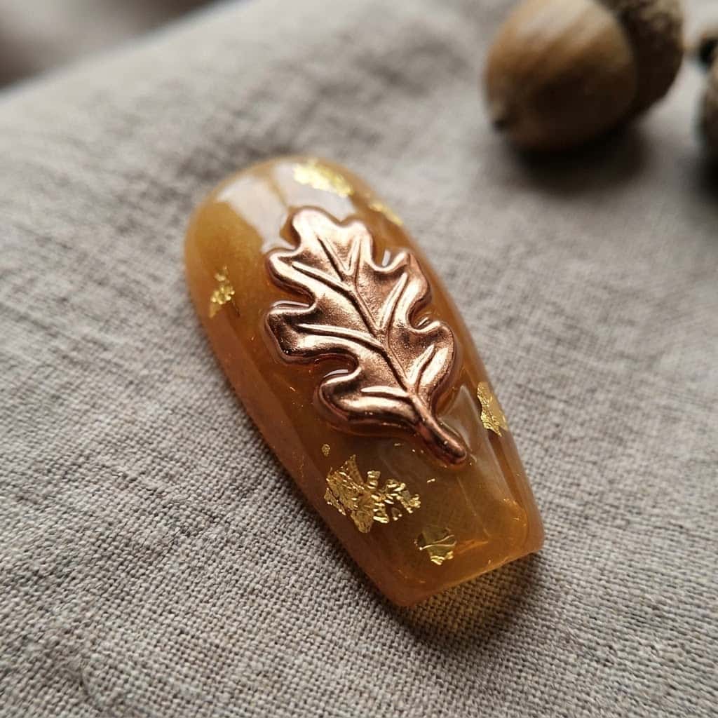 Close-up of the raised 3D copper oak leaf on an amber jelly coffin nail