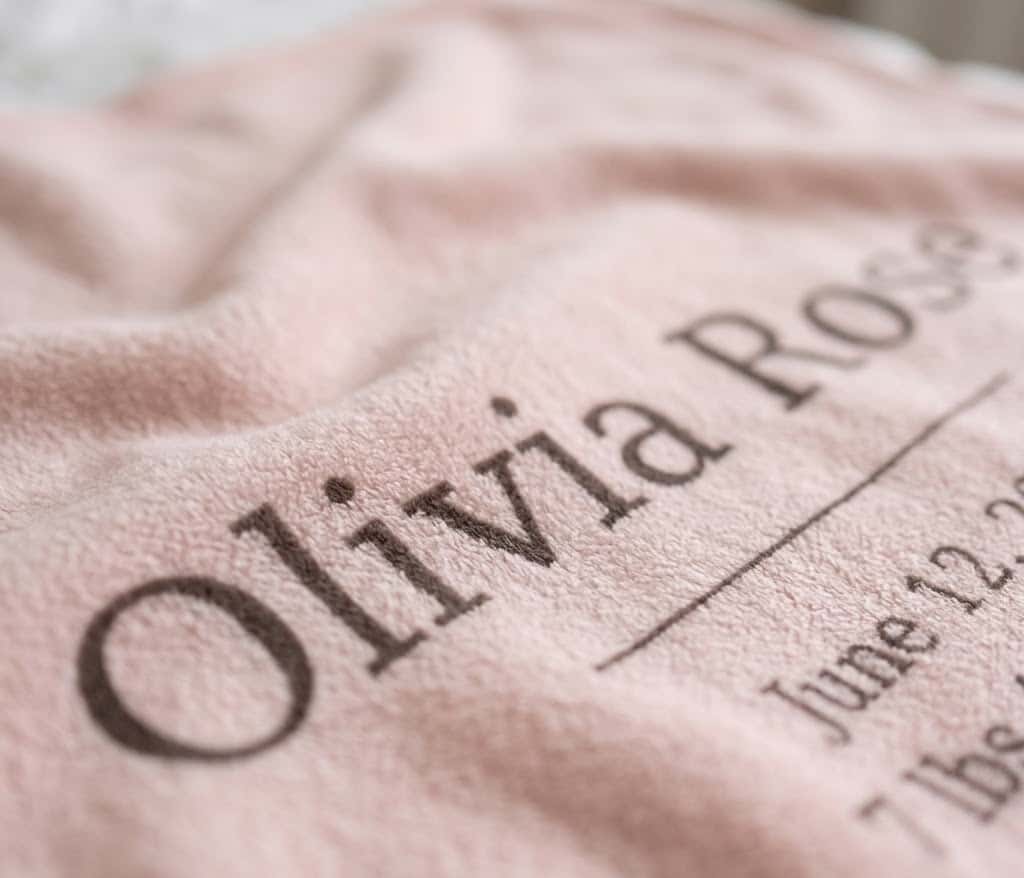 Close-up of serif Olivia Rose name and birth date on blush flannel