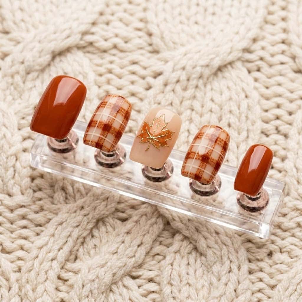One hand of burnt orange nails on a clear acrylic stand