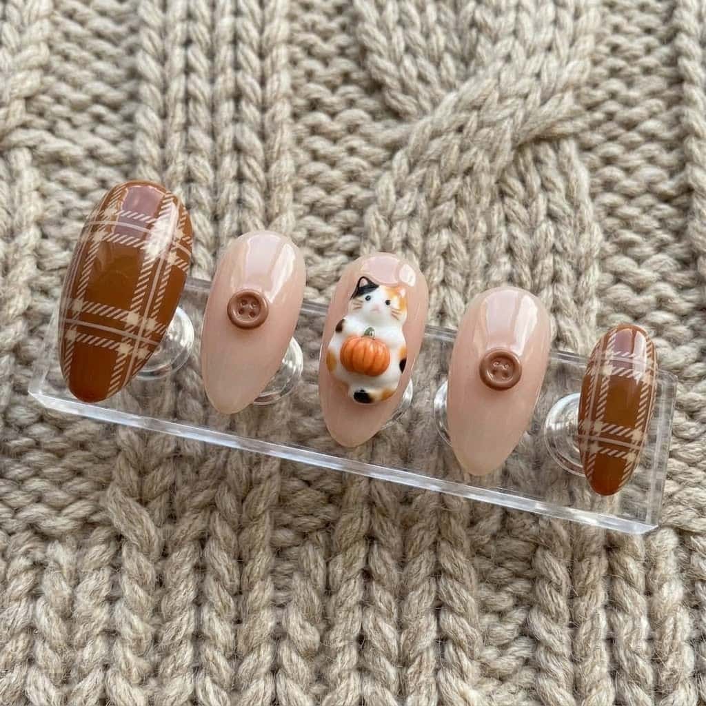 Five almond press on nails with plaid and buttons on a clear acrylic stand