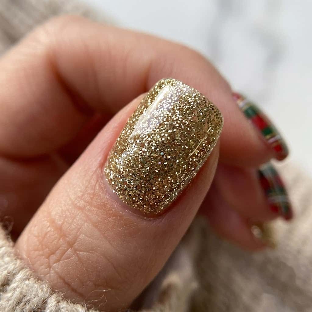 Close-up of a fine gold glitter accent nail beside plaid nails
