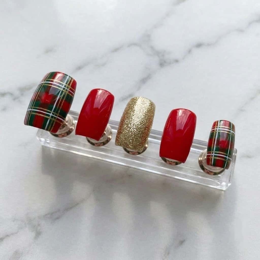 Five christmas plaid press on nails on a clear acrylic nail stand