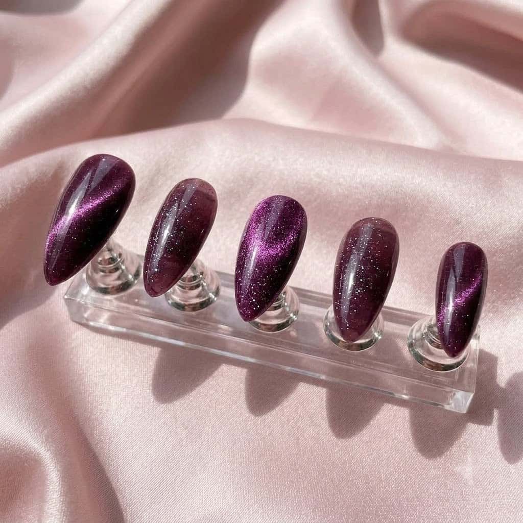Five glitter cat eye nails on a clear acrylic stand