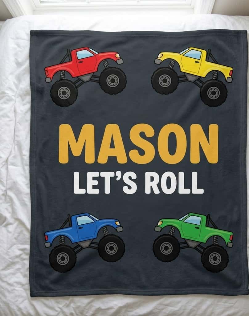 Monster truck name blanket with Mason in yellow on charcoal, flat on a bed