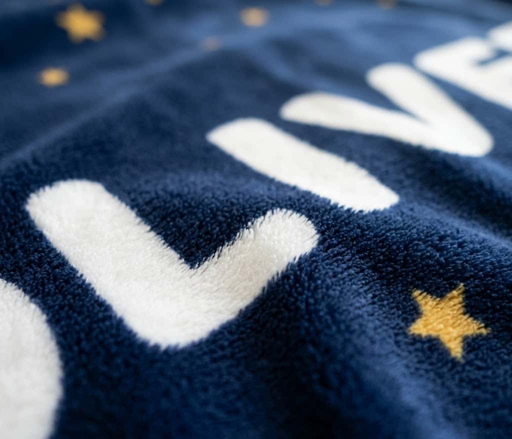 Close-up of rounded OLIVER lettering and gold star on soft flannel