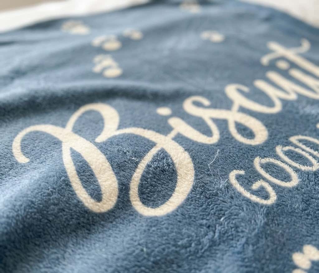 Close-up of cream Biscuit script and Good Boy line on flannel
