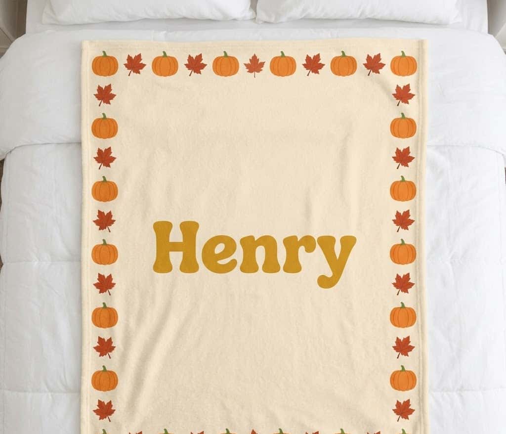 Pumpkin name blanket with Henry in mustard letters, flat on a bed