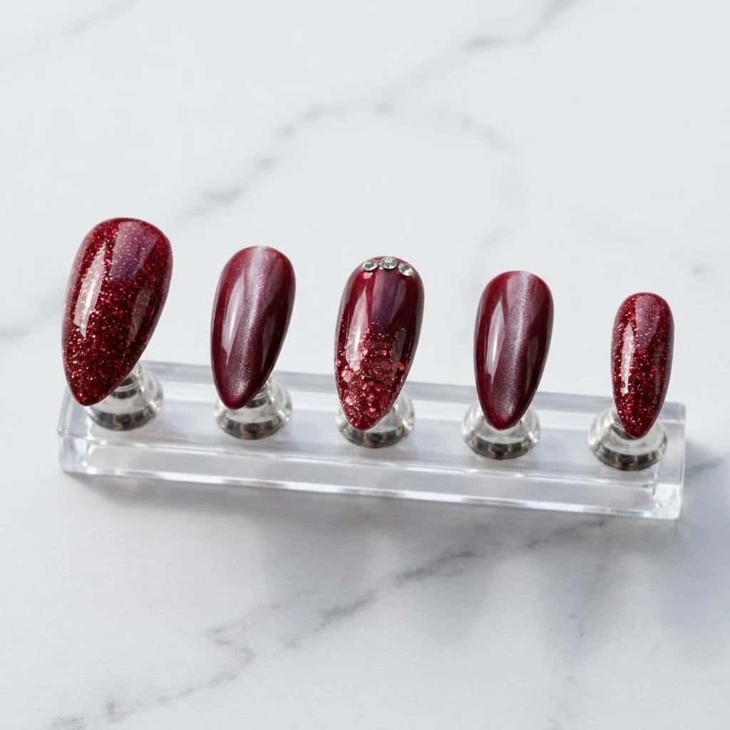 Five ruby glitter red cat eye press on nails on a clear acrylic stand