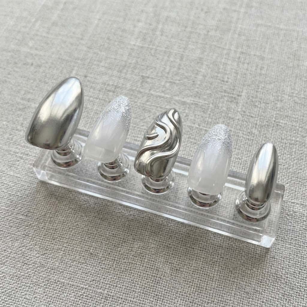 Five silver chrome nails on a clear acrylic stand