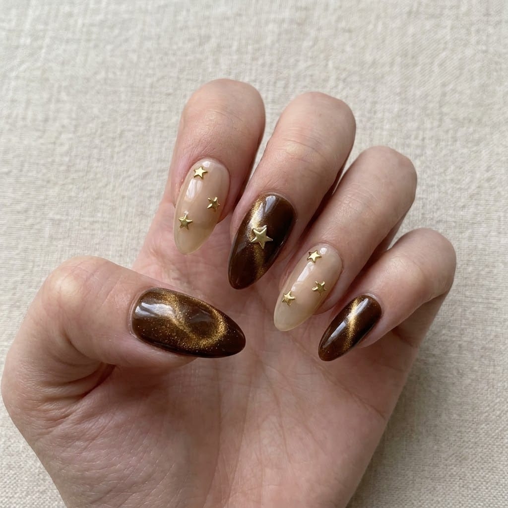 Hand wearing brown cat eye nails with the hero design on the middle finger