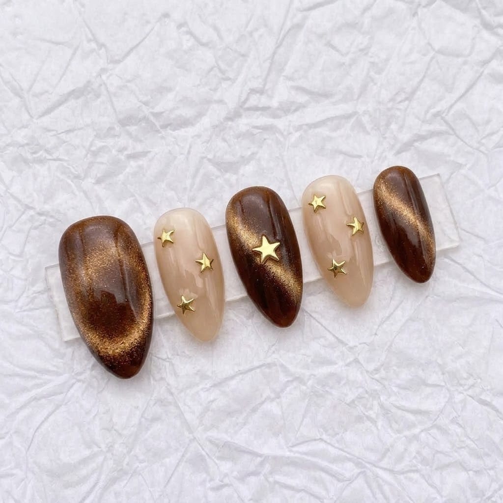 Five brown cat eye nails on a clear acrylic stand