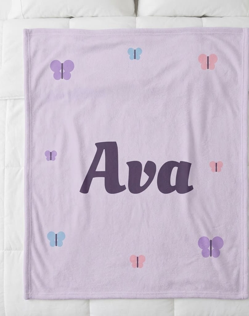 Butterfly name blanket with Ava in plum script on lavender, flat on a bed