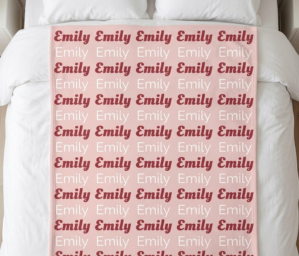 Girl name repeat blanket with Emily in rose and white rows on a bed
