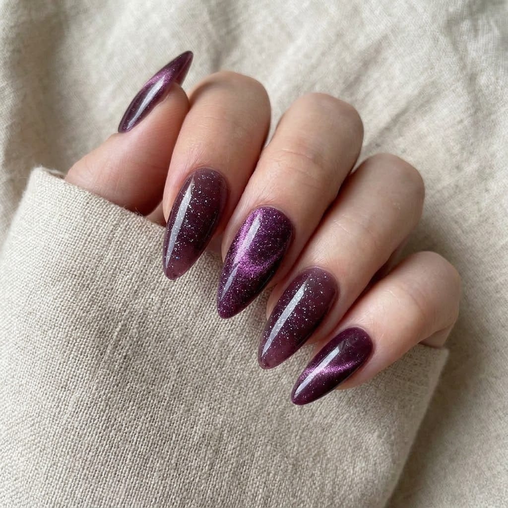 Hand wearing glitter cat eye nails with the hero design on the middle finger