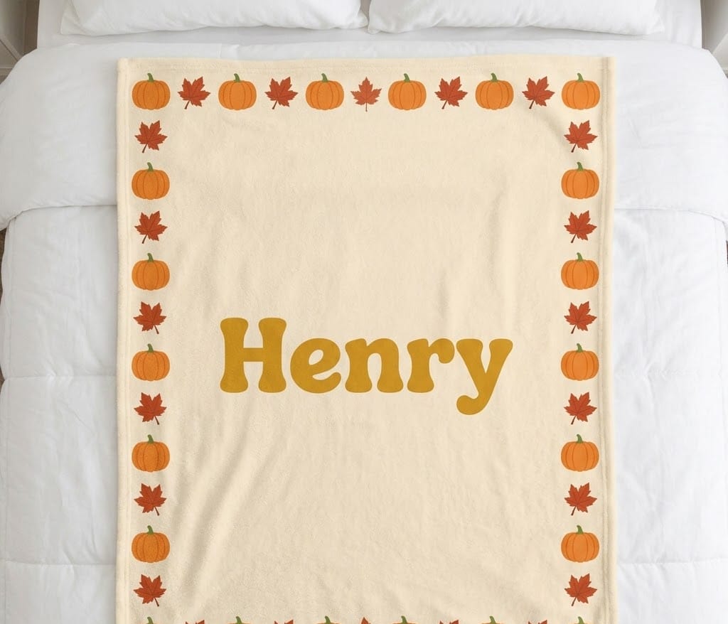 Pumpkin name blanket with Henry in mustard letters, flat on a bed