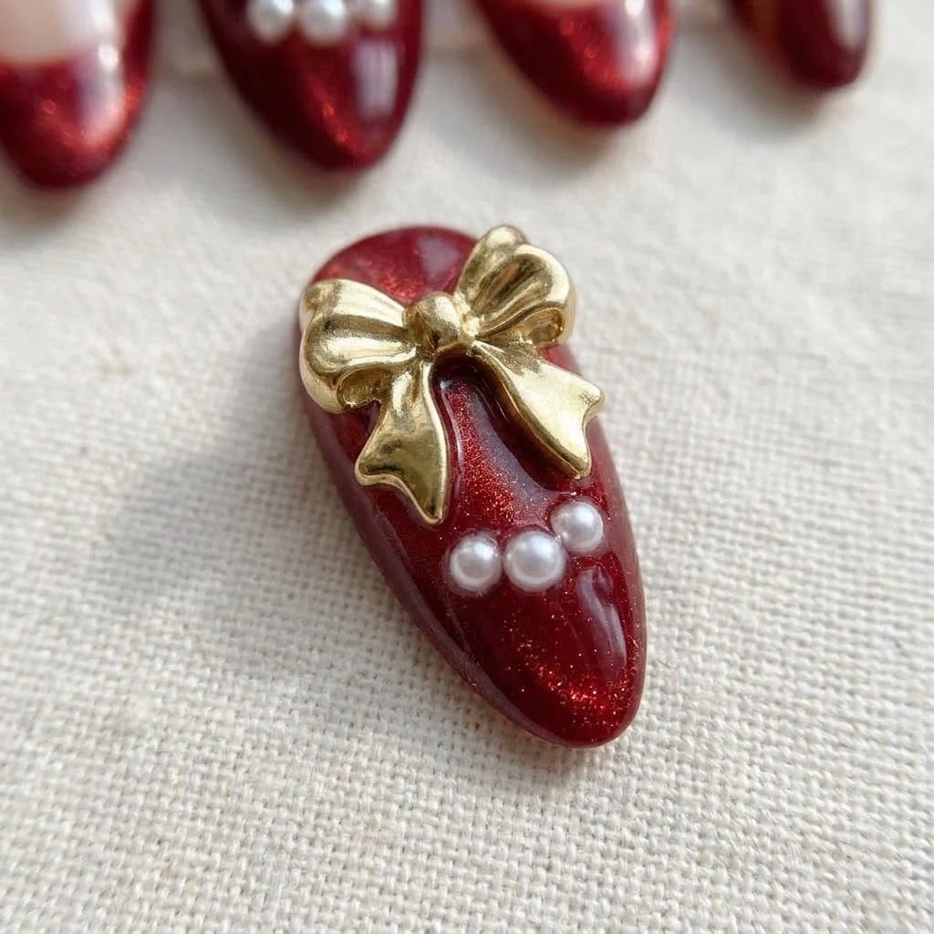 Close-up of ruby cat eye nail with 3D gold bow and pearls