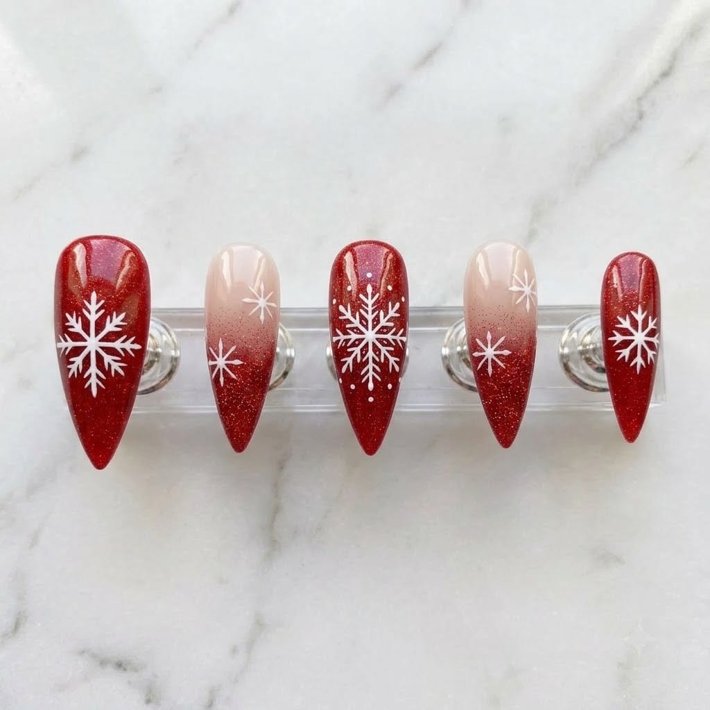 Five red snowflake stiletto nails on a clear acrylic stand