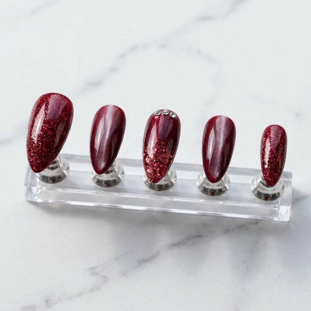 Five ruby glitter red cat eye press on nails on a clear acrylic stand