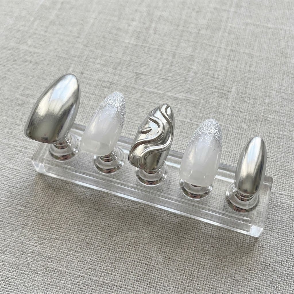 Five silver chrome nails on a clear acrylic stand